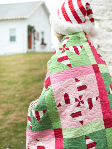 woman outdoors with red and green christmas quilt wrapped around her shoulders