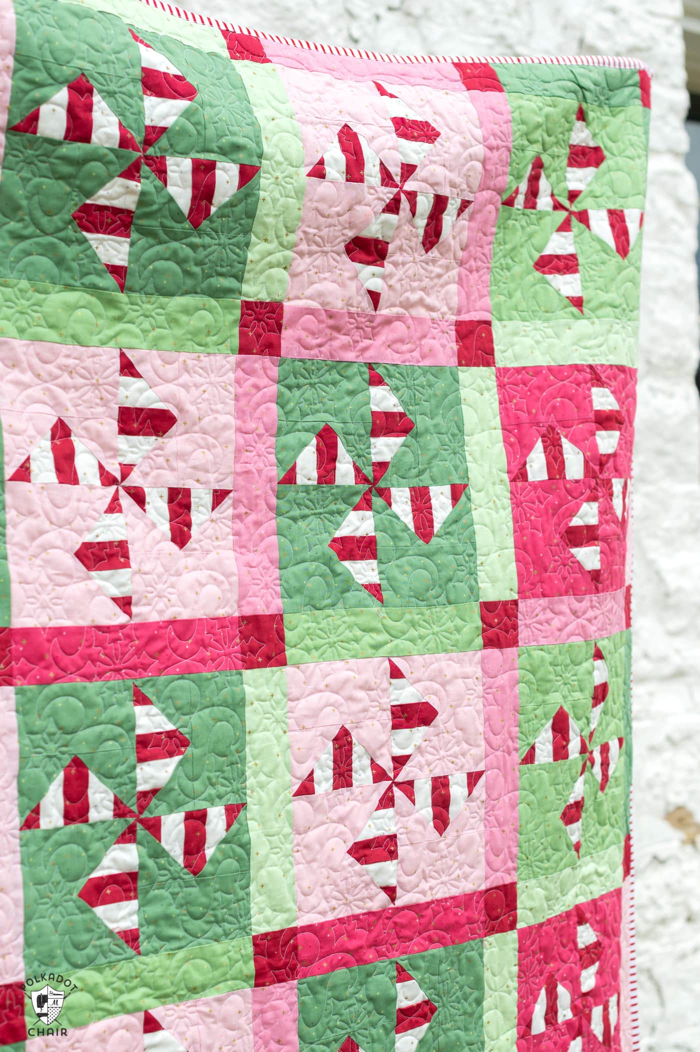 woman holding red, white, pink and green christmas quilt outdoors