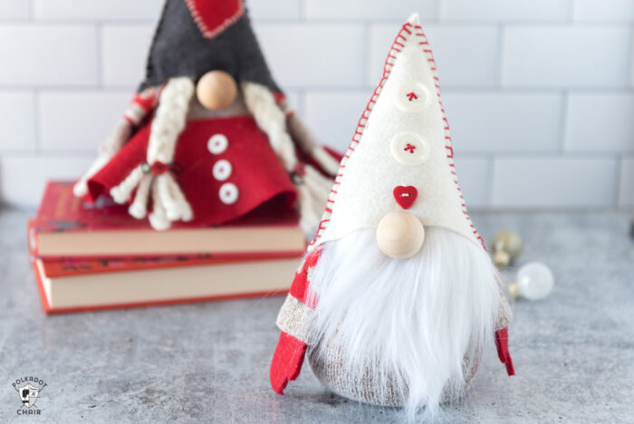 Red & gray stuffed Christmas gnomes on white countertop with books