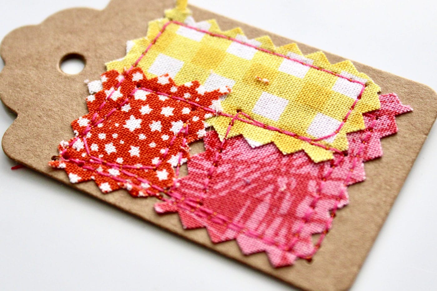close up of colorful fabric and paper gift tags on white wood table