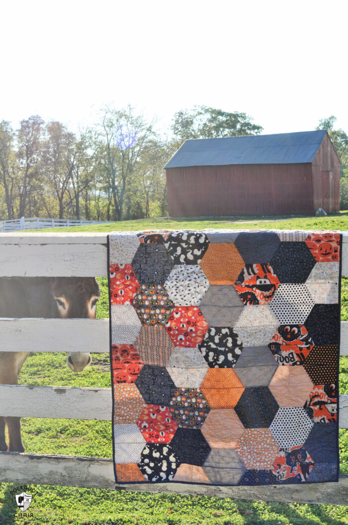 close up of large hexagon quilt with orange, ivory and gray blocks