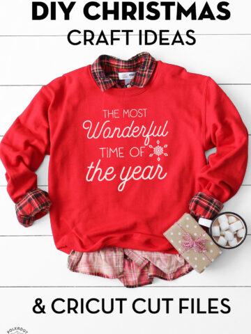 red sweatshirt with white lettering on white table with christmas props.