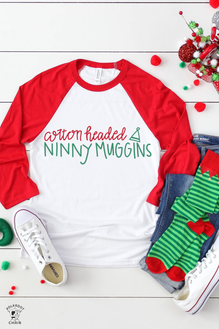 red sweatshirt with white lettering on white table with christmas props.