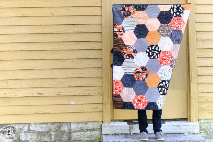 sewn hexagon quilt being held by person outdoors