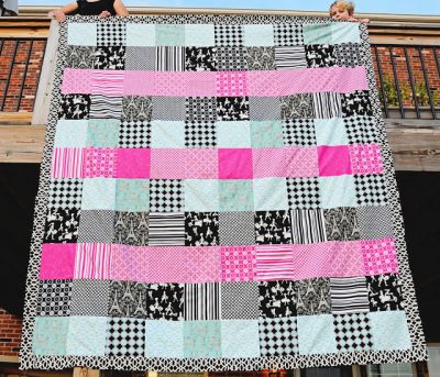 pink, aqua and black queen sized quilt hanging on deck