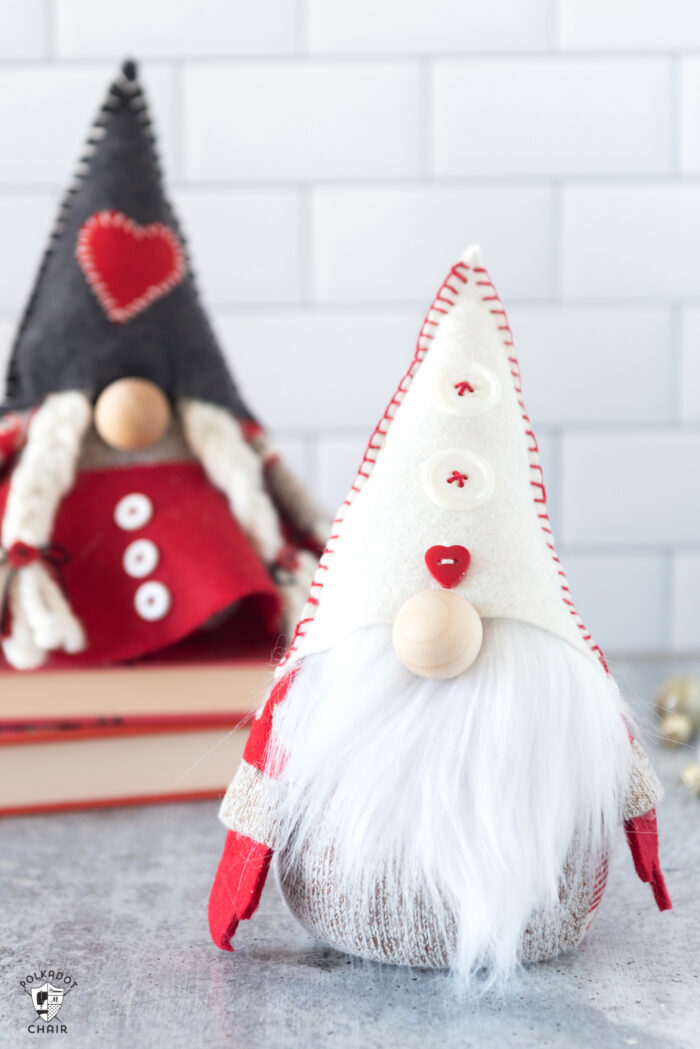 Red & gray stuffed Christmas gnomes on white countertop with books