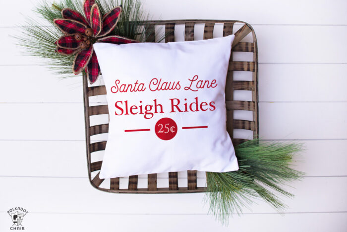 white pillow with red christmas lettering on white table with basket