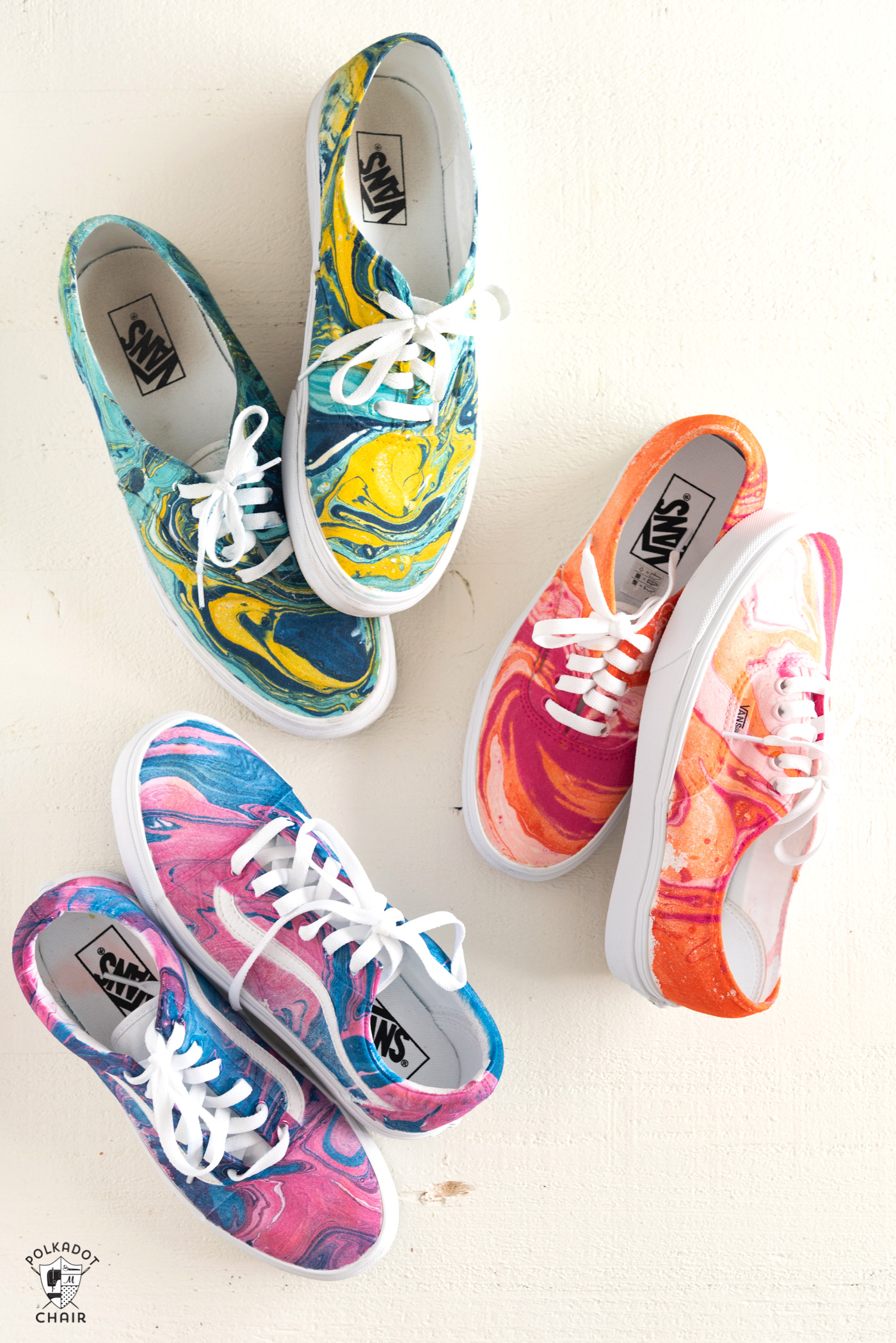Three pairs of lace up sneakers. One pair is a pink, orange, and white marble, one is pink and blue marble, and the third blue and yellow marble. 