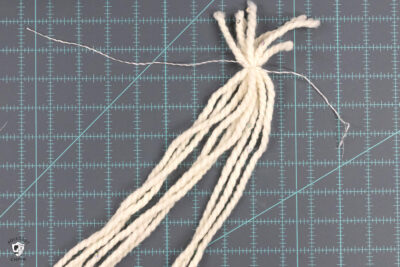 strands of thick yarn tied together on cutting mat